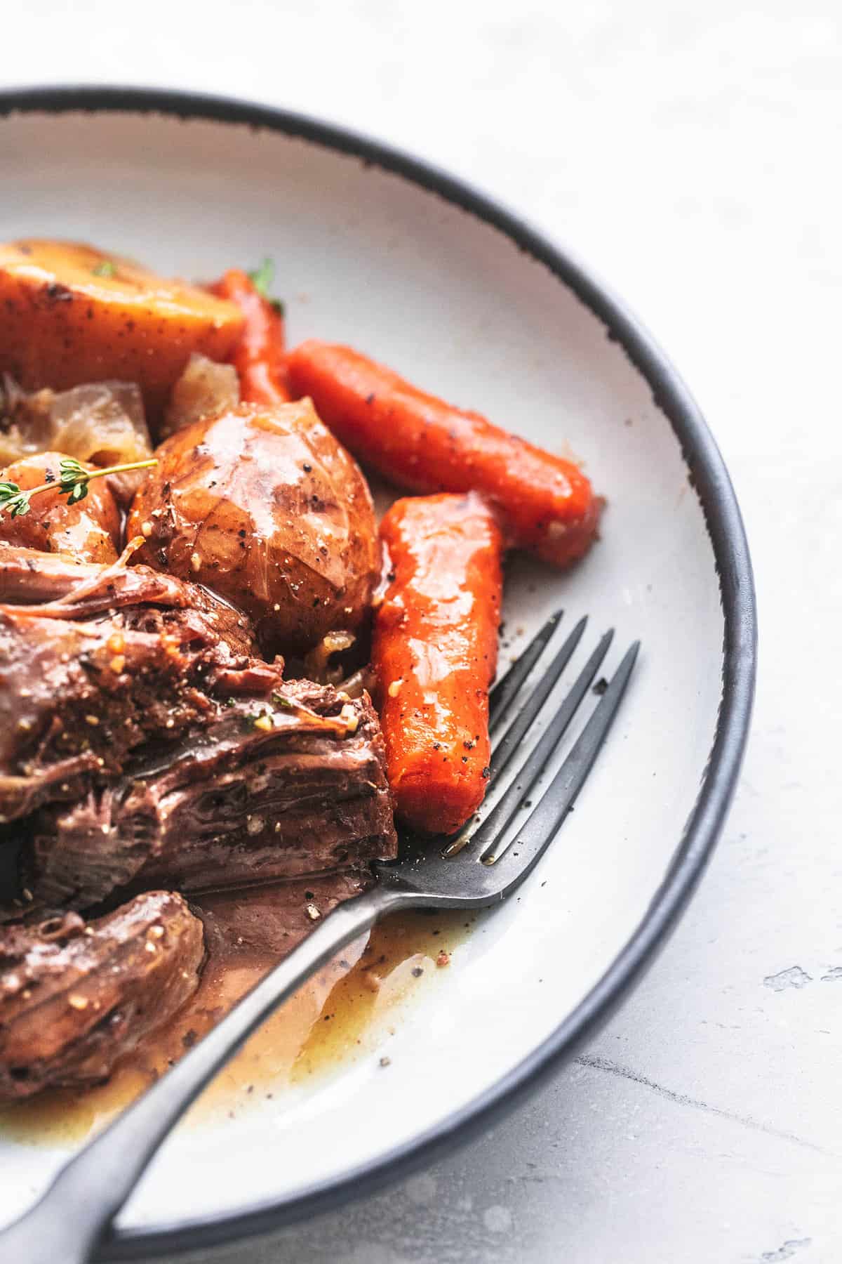 close up of slow cooker beef roast with a fork on a plate.