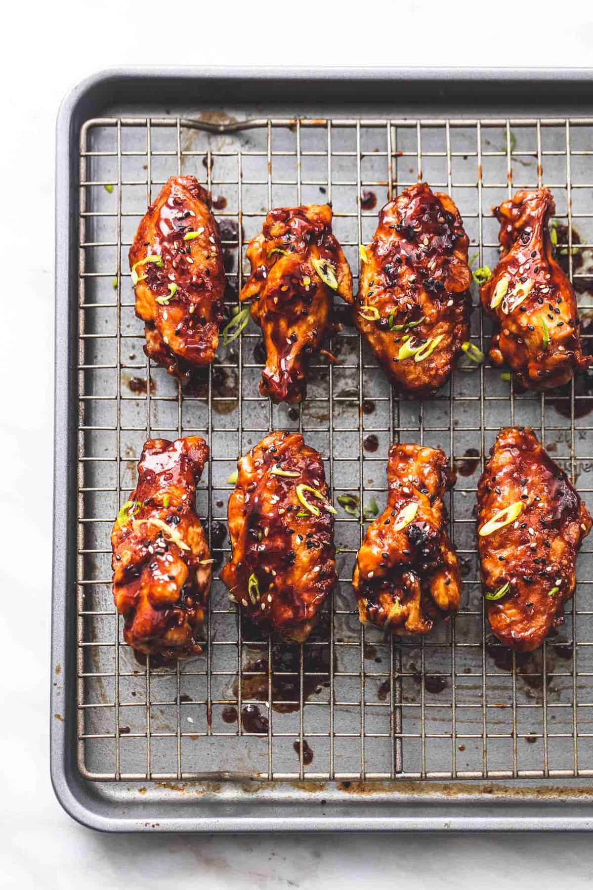 top view of spicy Korean bbq chicken wings on a cooling rack on a baking sheet.