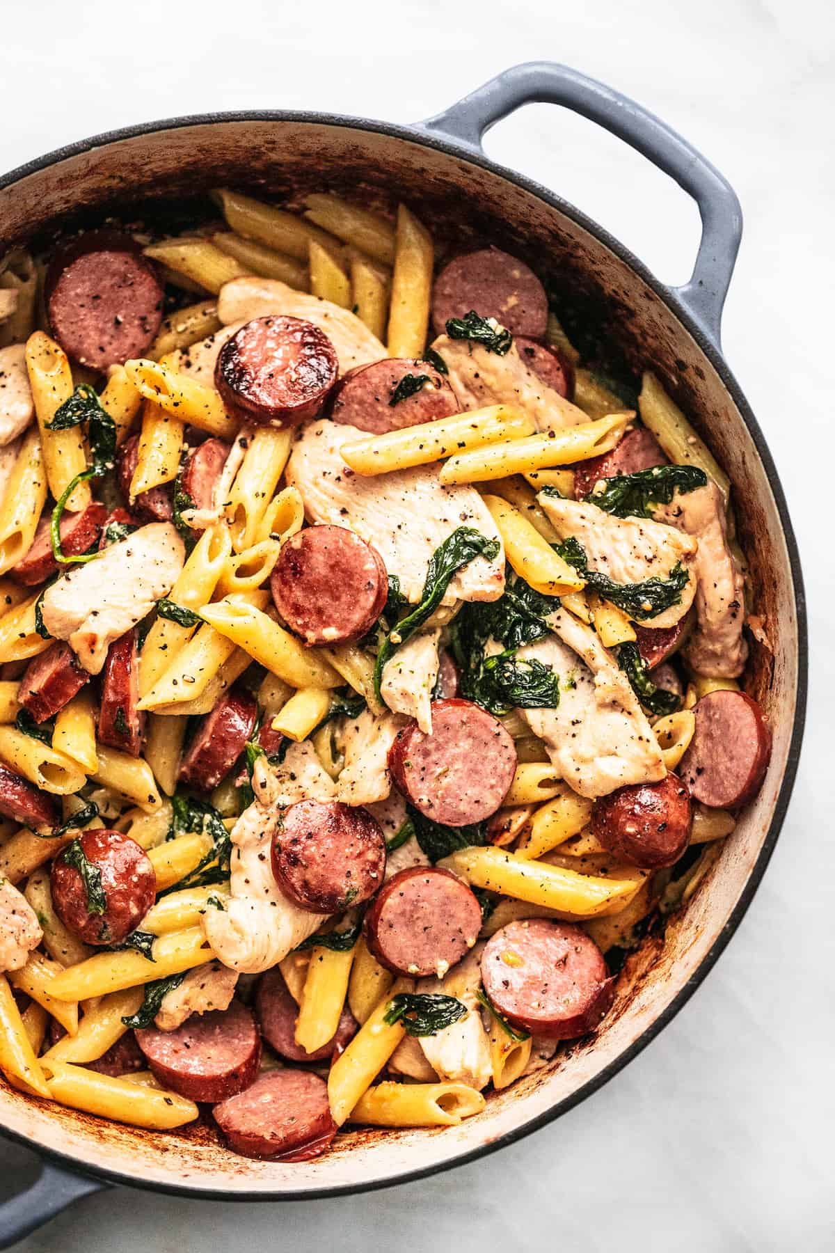 close up top view of chicken and sausage pasta in a pan.