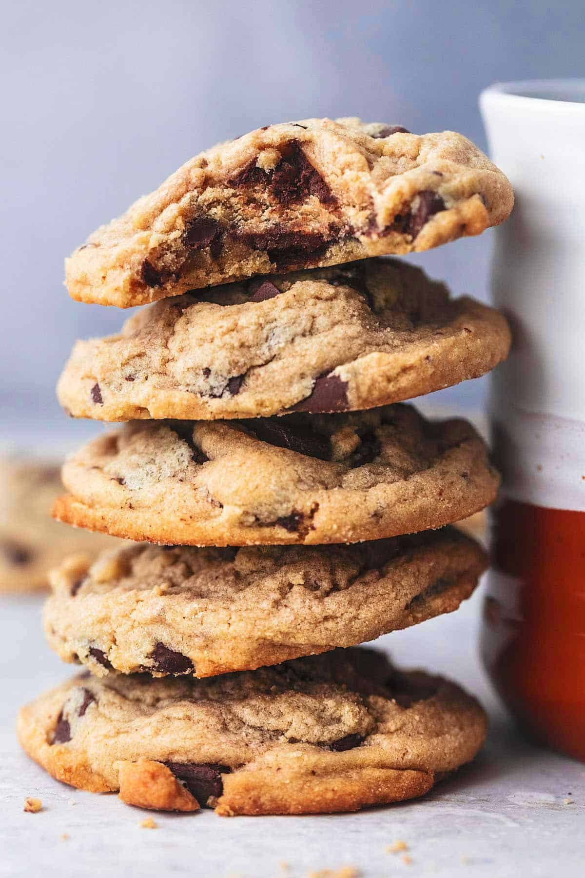peanut butter chocolate chunk cookies stacked against a mug with the top cookie missing a bite.