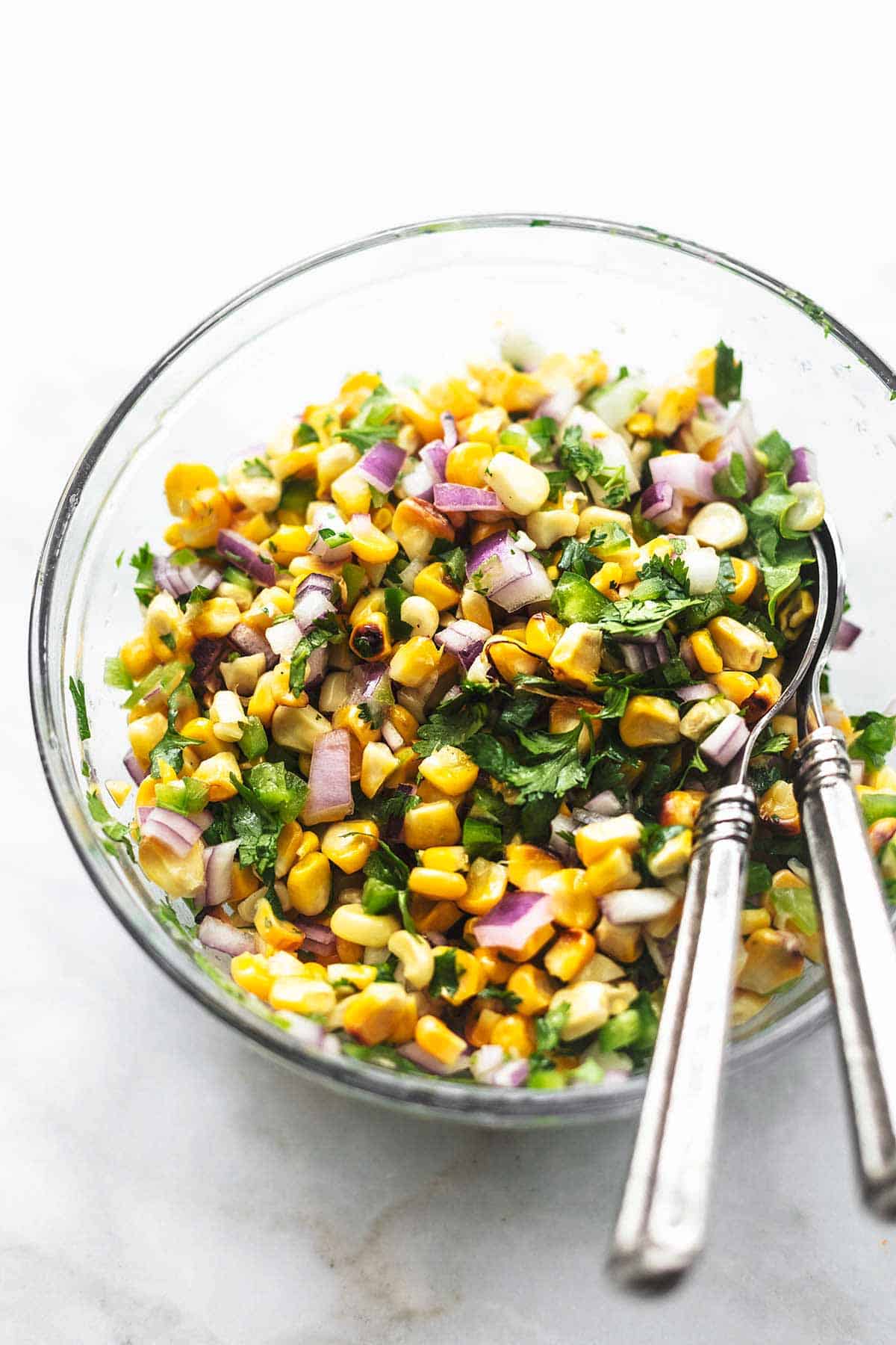 corn salsa in a glass bowl with two spoons