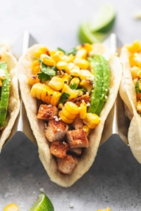 up close single chicken taco in taco holder topped with corn salsa