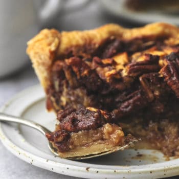 up close bite of pecan pie on fork in front of pie slice