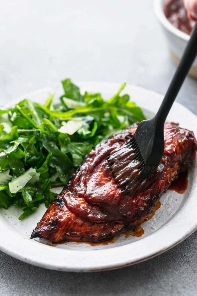 basting brush spreading bbq sauce onto grilled chicken breast