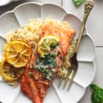 grilled salmon with lemon butter sauce and orzo on plate with fork