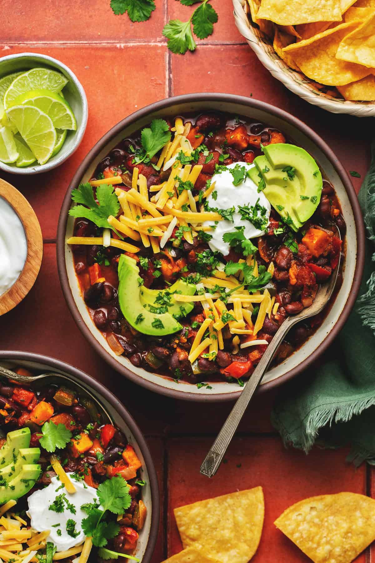 two bowls of chili with cheese, avocado, and sour cream toppings