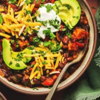 overhead view of bowl of chili with toppings and spoon in bowl