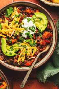 overhead view of bowl of chili with toppings and spoon in bowl