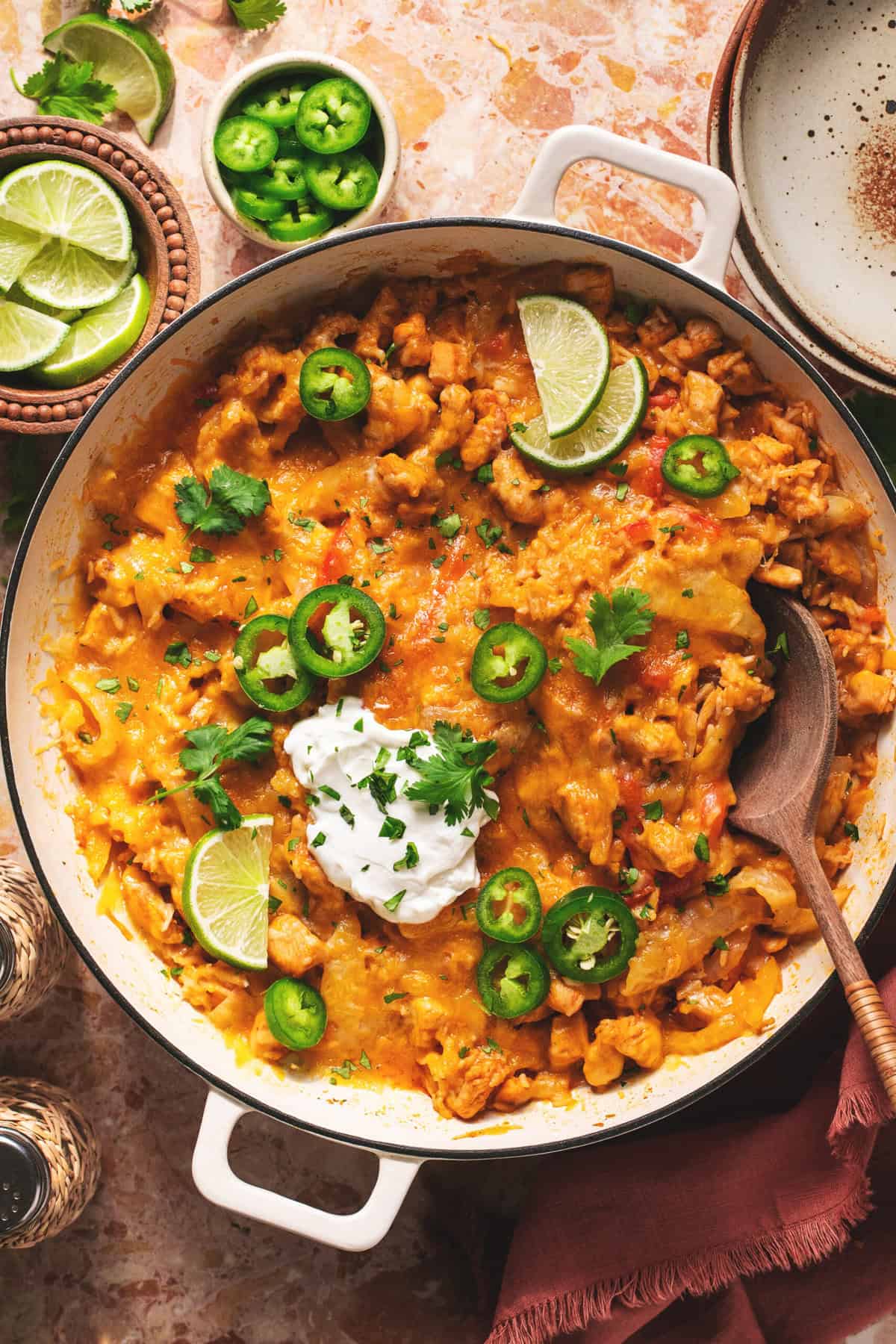 skillet with cheesy mexican chicken and rice topped with jalapenos and sour cream