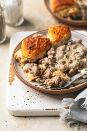 biscuits and sausage gravy in bowl with fork on cutting board