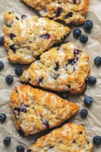 blueberry scones with vanilla glaze and fresh blueberries on parchment