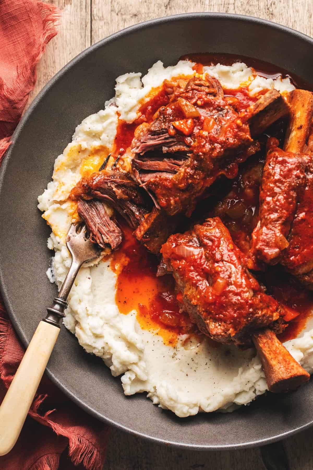 fork pulled meat off of short rib bone over potatoes