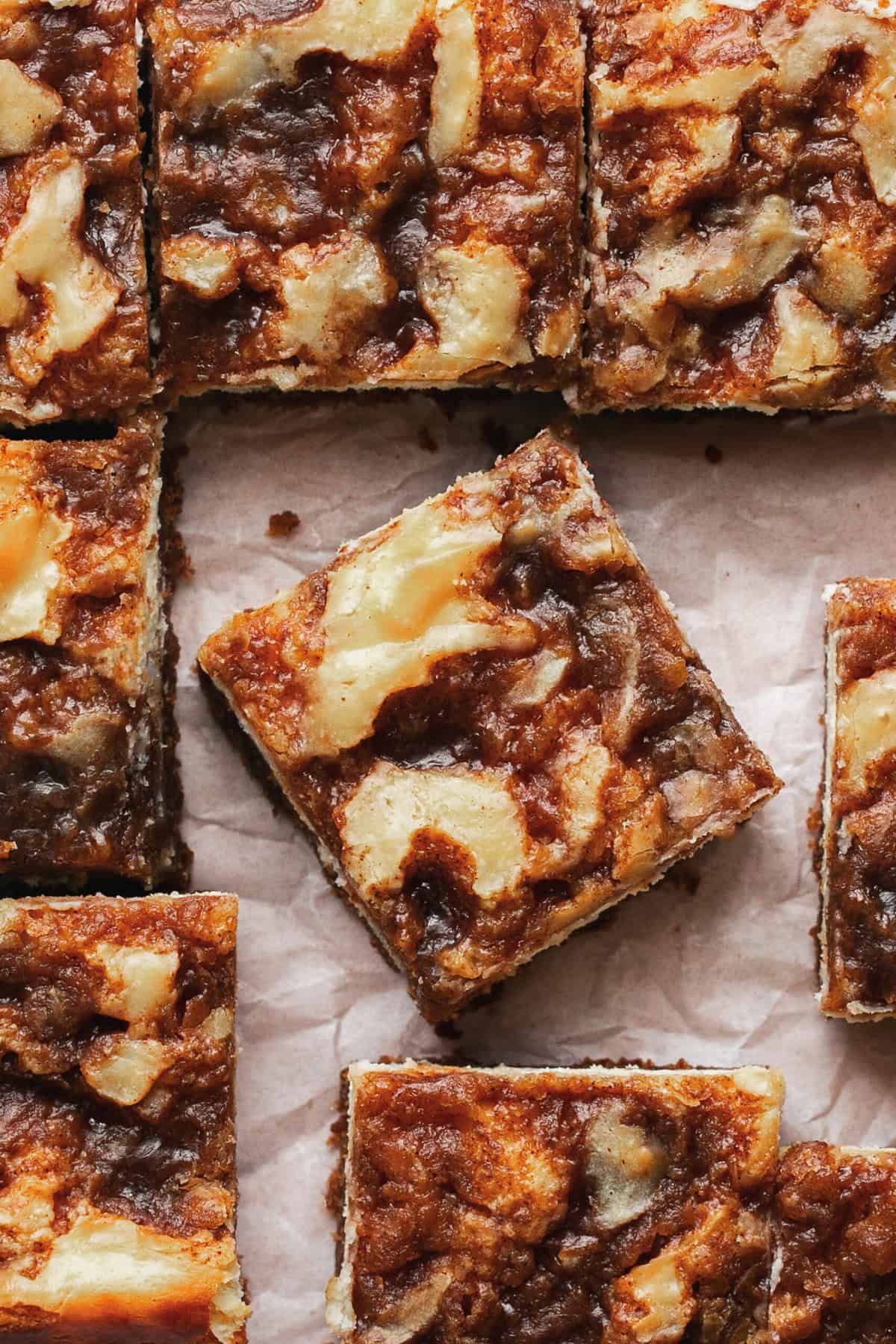 cinnamon swirl cheesecake bars cut side by side on parchment