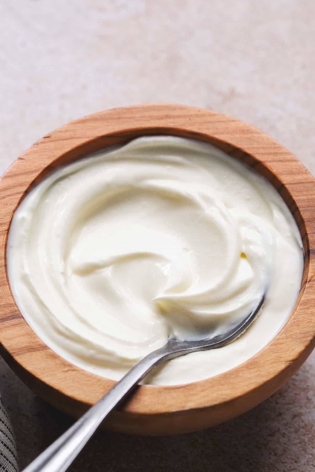 sour cream in wooden bowl with spoon