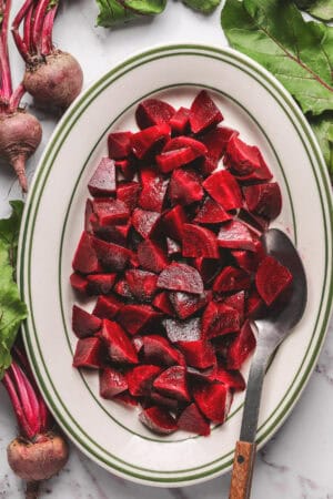 platter of oven roasted beets with serving spoon and whole beets on the side