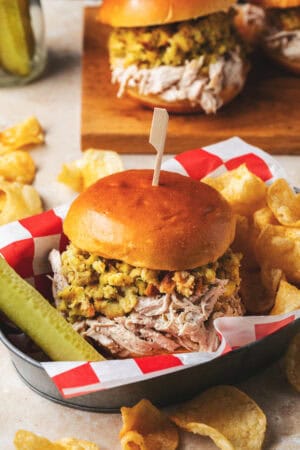 shredded chicken and stuffing sandwich with pickle and chips in basket