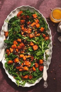 platter and serving spoon with arugula and butternut squash salad