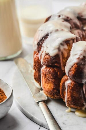 up close monkey bread with icing on marble slab with knife