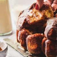 hand pulling piece of cinnamon monkey bread with vanilla glaze