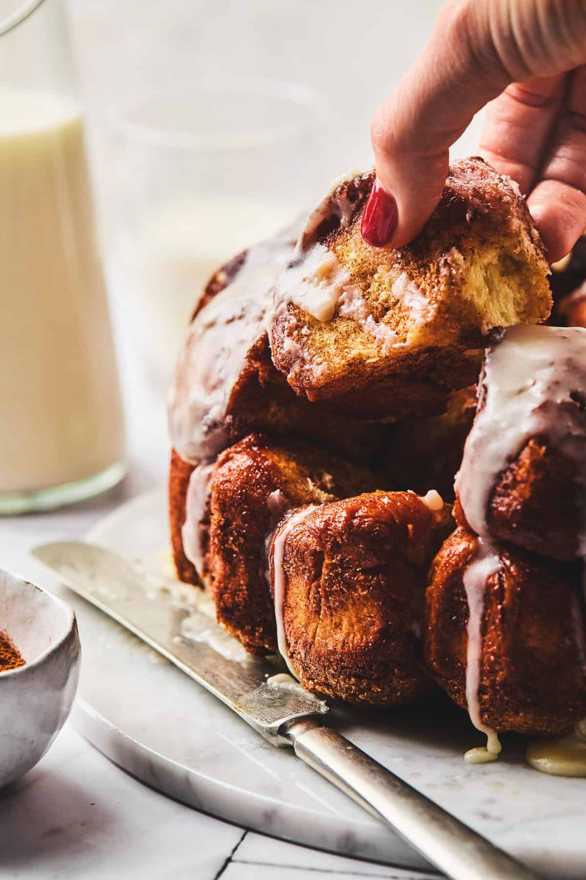 hand pulling piece of cinnamon monkey bread with vanilla glaze