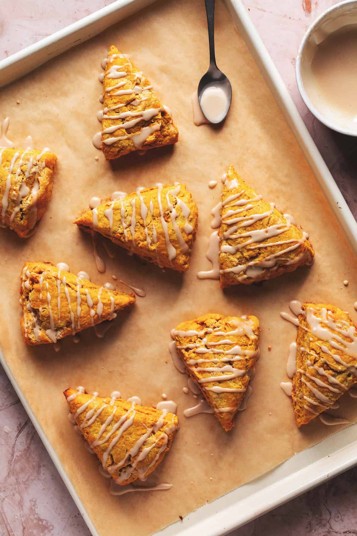 maple glazed pumpkin scones on parchment-lined baking sheet