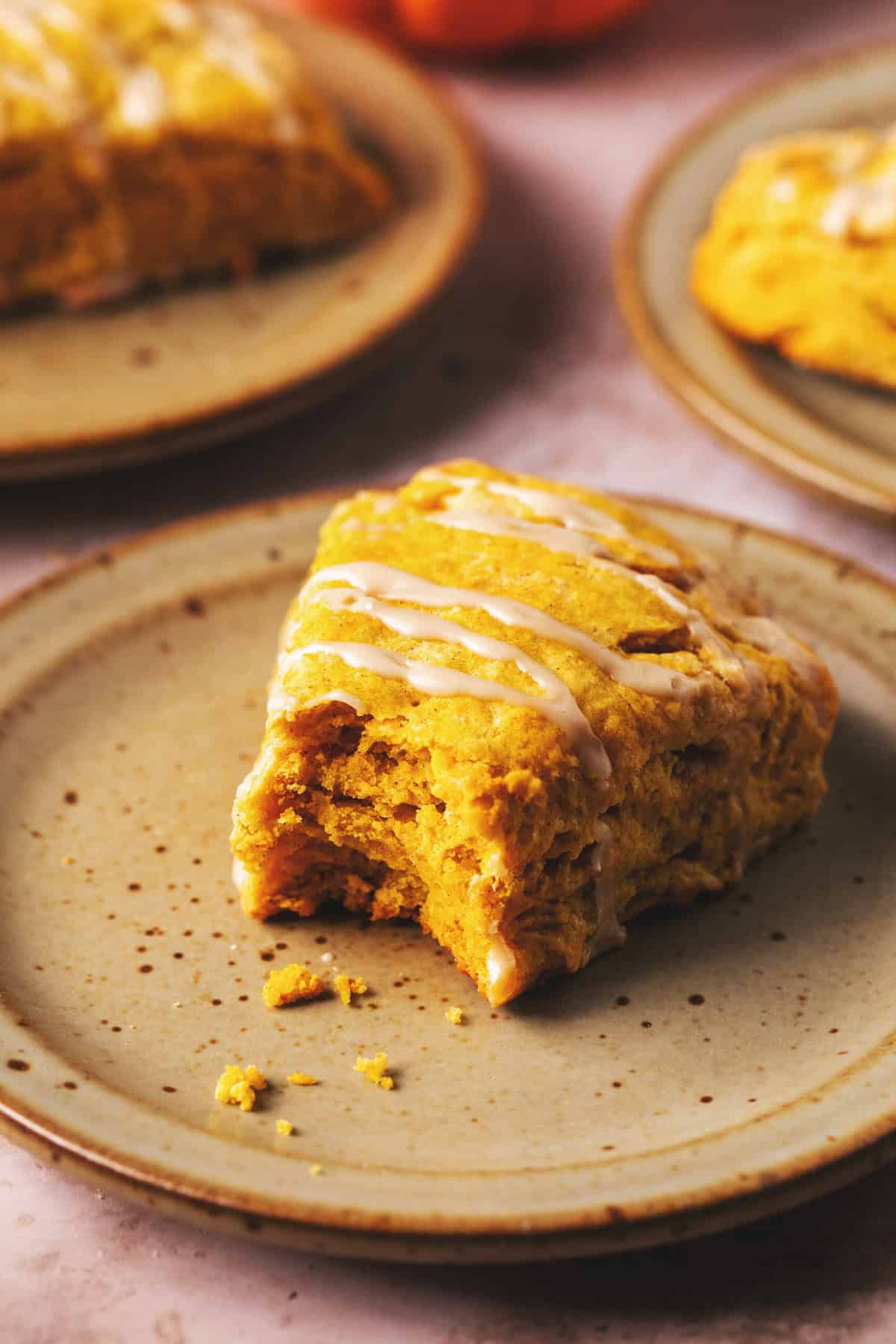 single pumpkin scone on a plate with bite missing