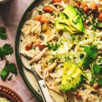 crockpot creamy white chicken chili with avocado and cilantro garnish