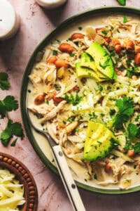 crockpot creamy white chicken chili with avocado and cilantro garnish