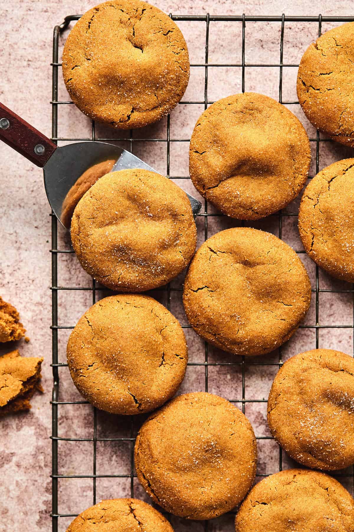 spatula lifting gingersnap cookie from cookie sheet with more cookies