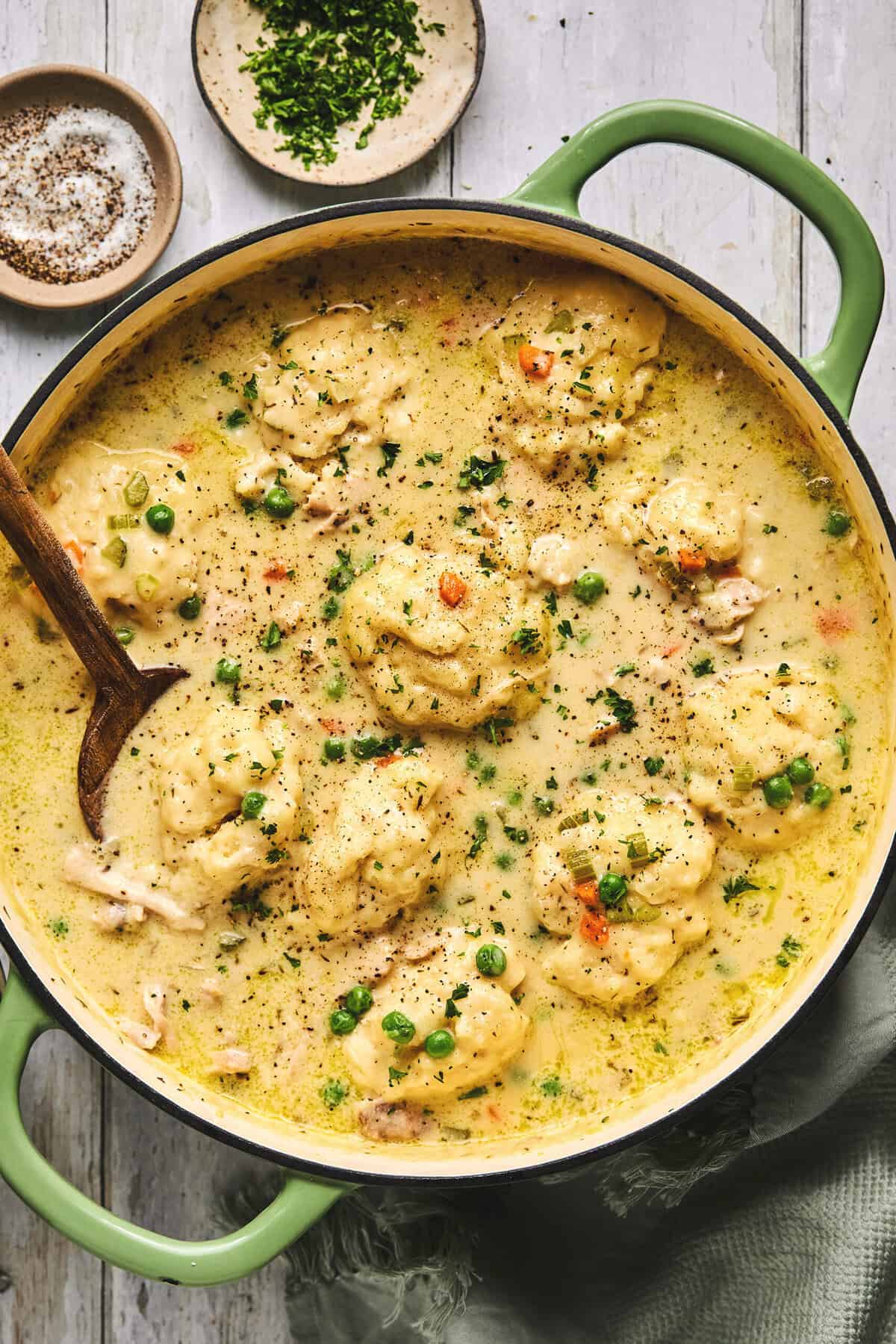 chicken dumpling soup in a pot with wooden serving spoon