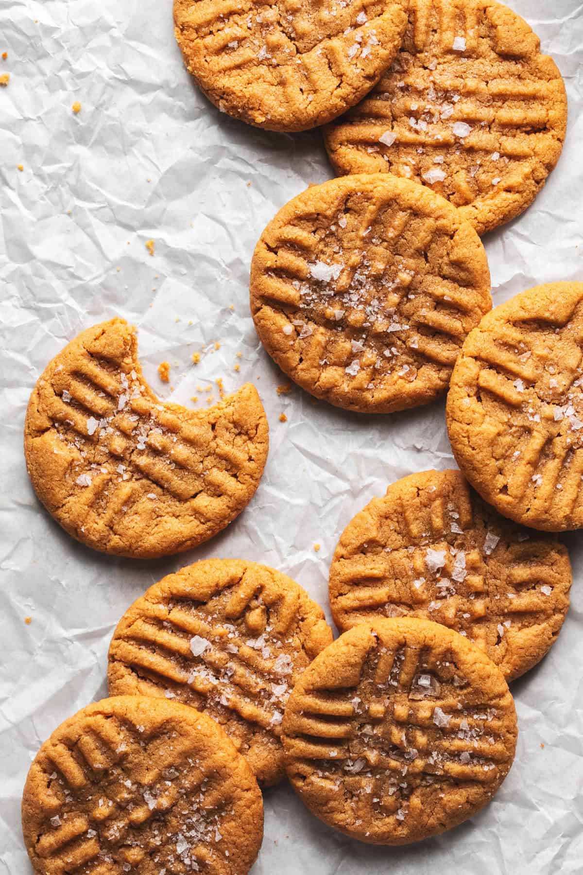 flourless peanut butter cookies on parchment paper with one cookie missing bite