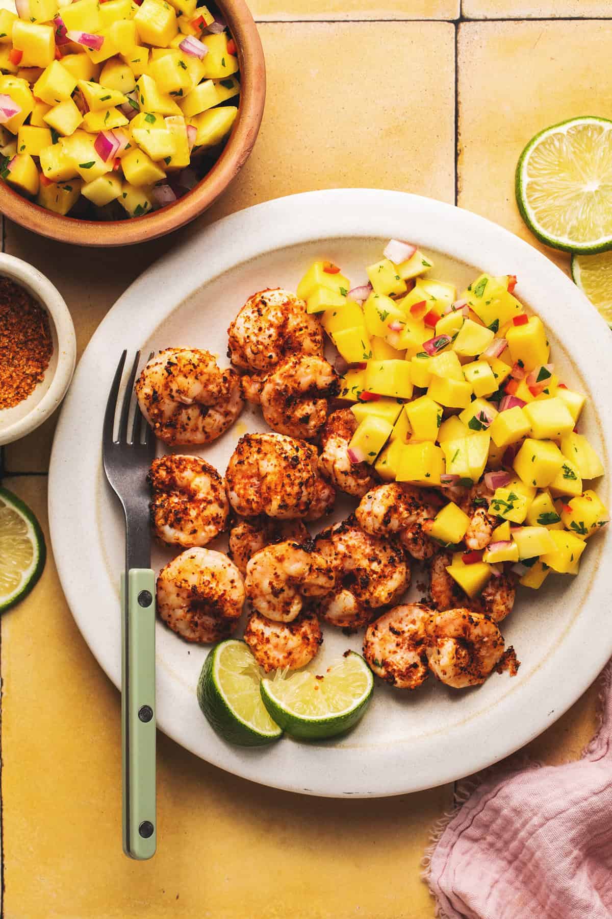 plate of shrimp with mango salsa and lime wedges