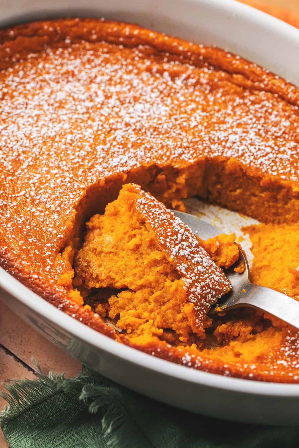 serving spoon scooping carrot souffle from casserole dish