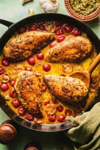 chicken in tomato and cream sauce in skillet with wooden serving spoon