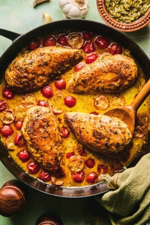 chicken in tomato and cream sauce in skillet with wooden serving spoon