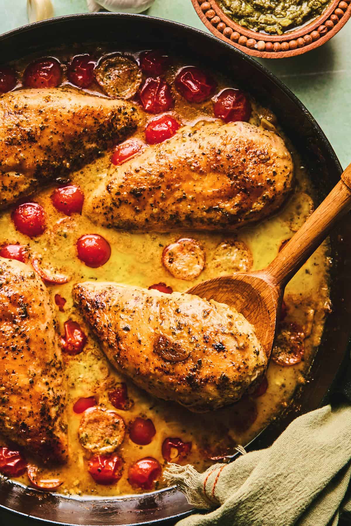 chicken in tomato and cream sauce in skillet with wooden serving spoon