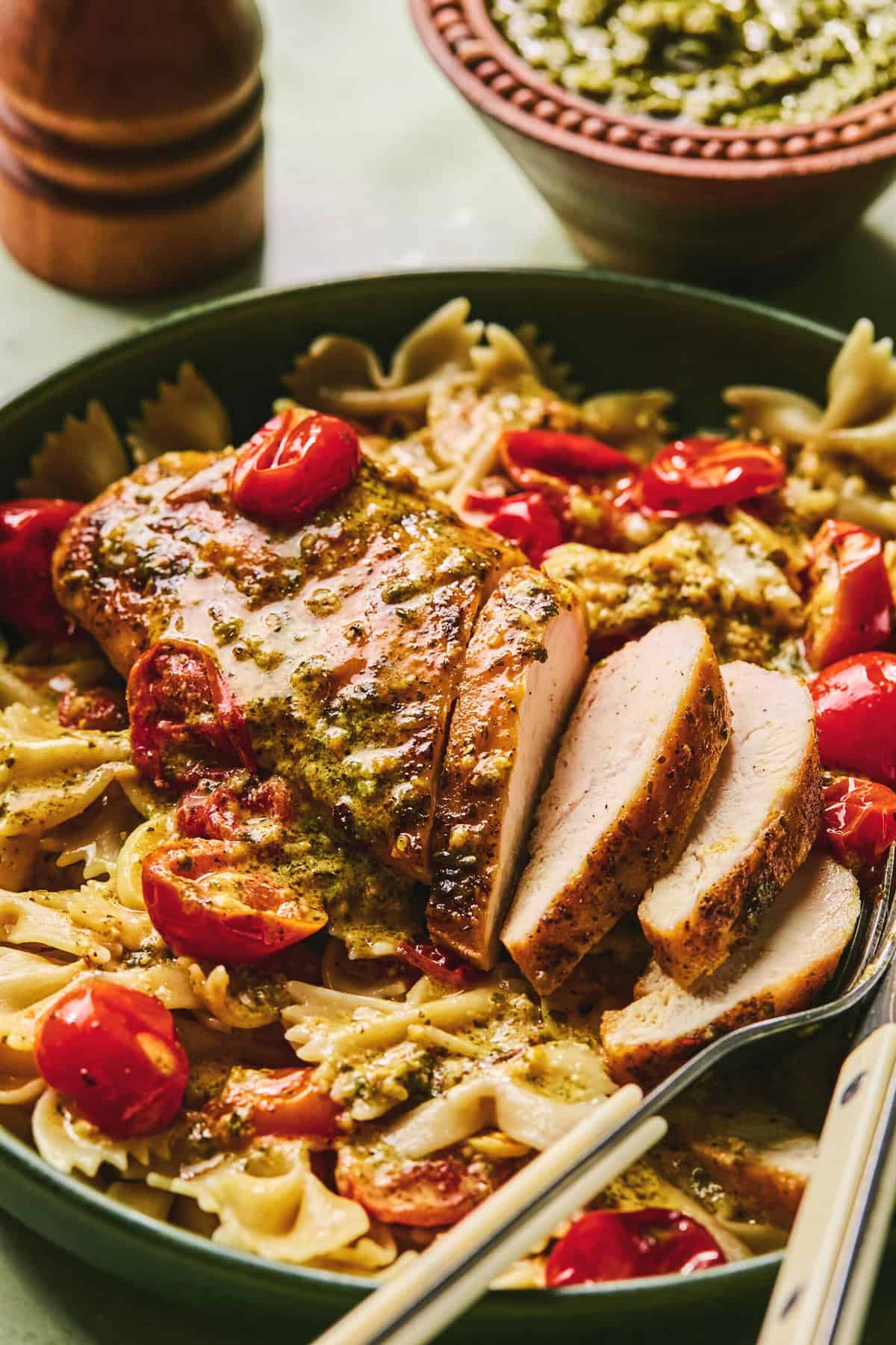 sliced chicken breast in pesto and tomato cream sauce with bowtie pasta