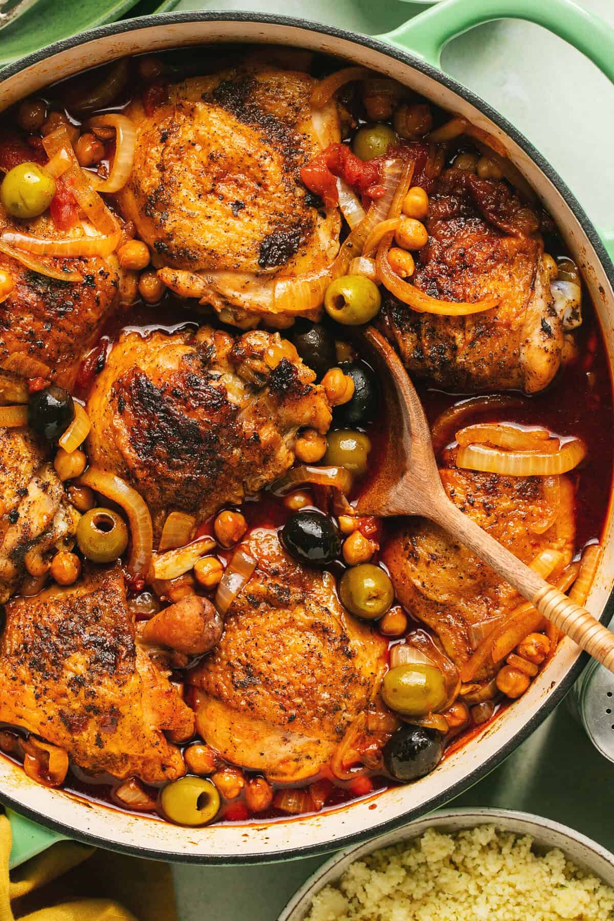 moroccan chicken tagine in skillet with wooden serving spoon