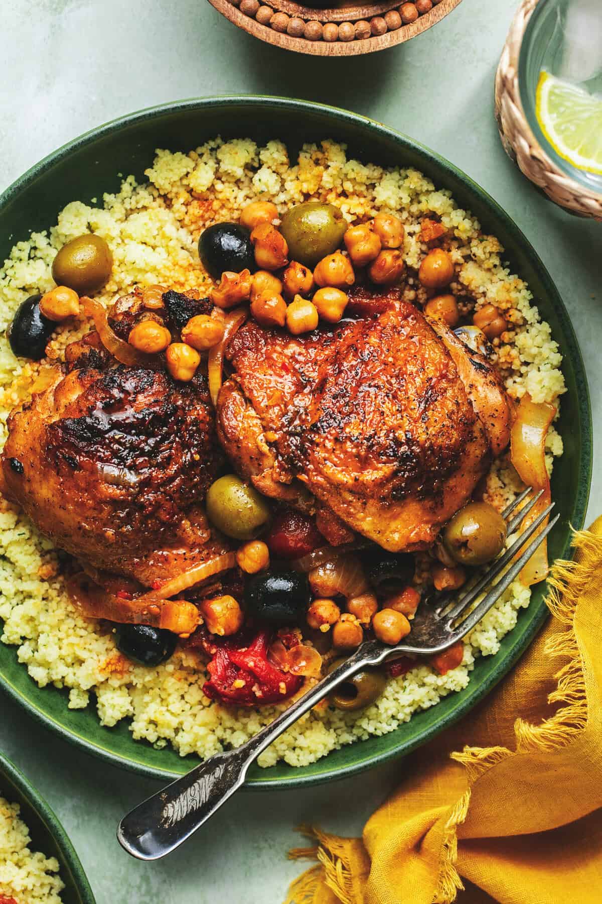 plate of roasted chicken thighs with tomatoes, olives, chickpeas, and couscous