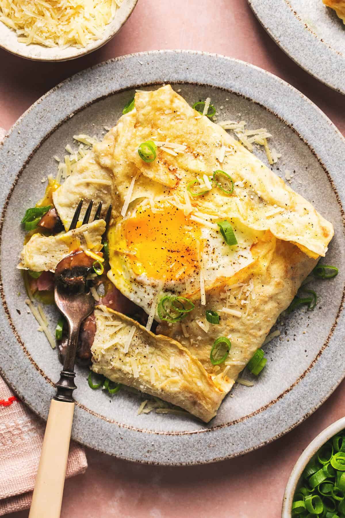 crepe filled with egg and ham on plate with fork