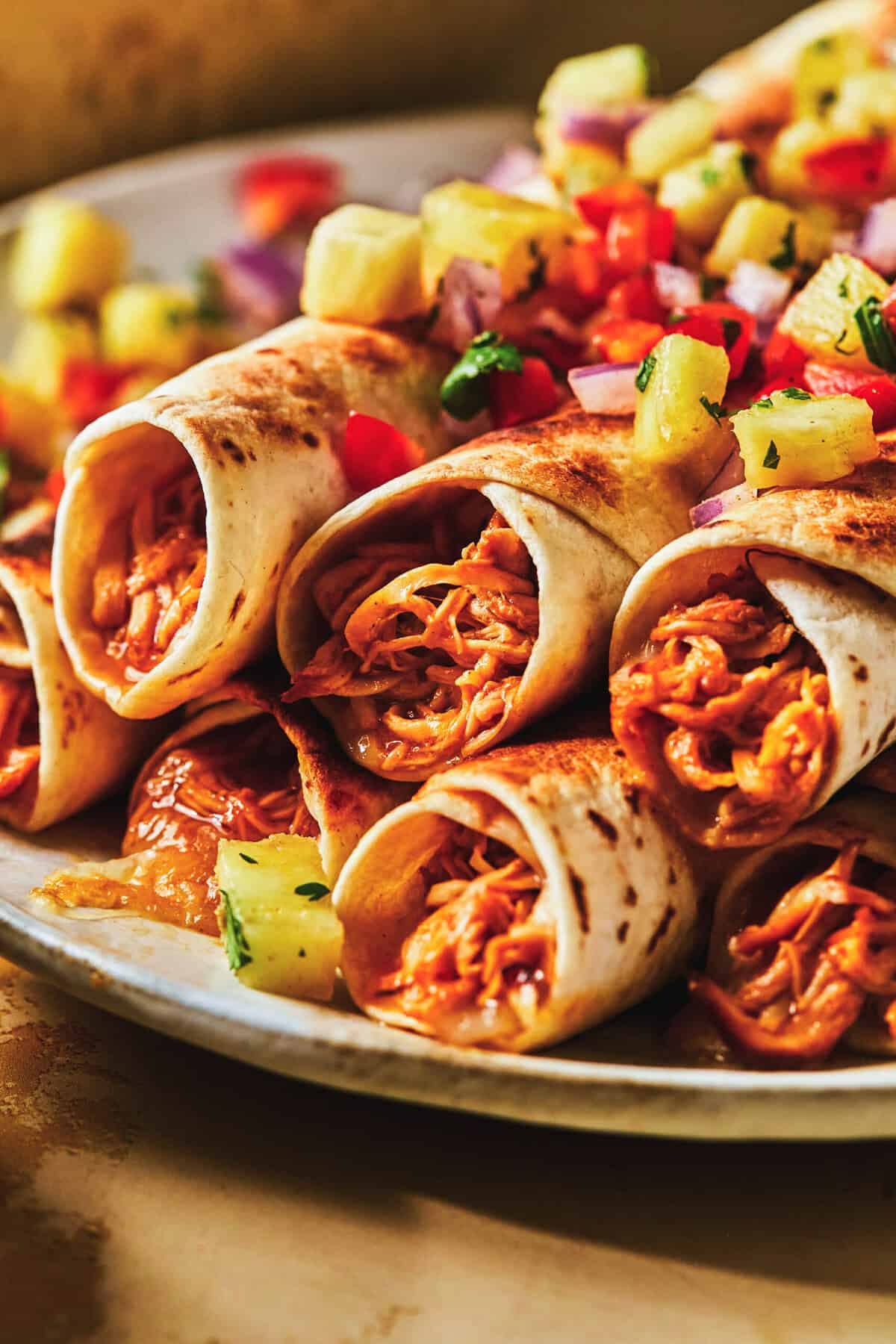 rolled shredded chicken taquitos stacked on plate