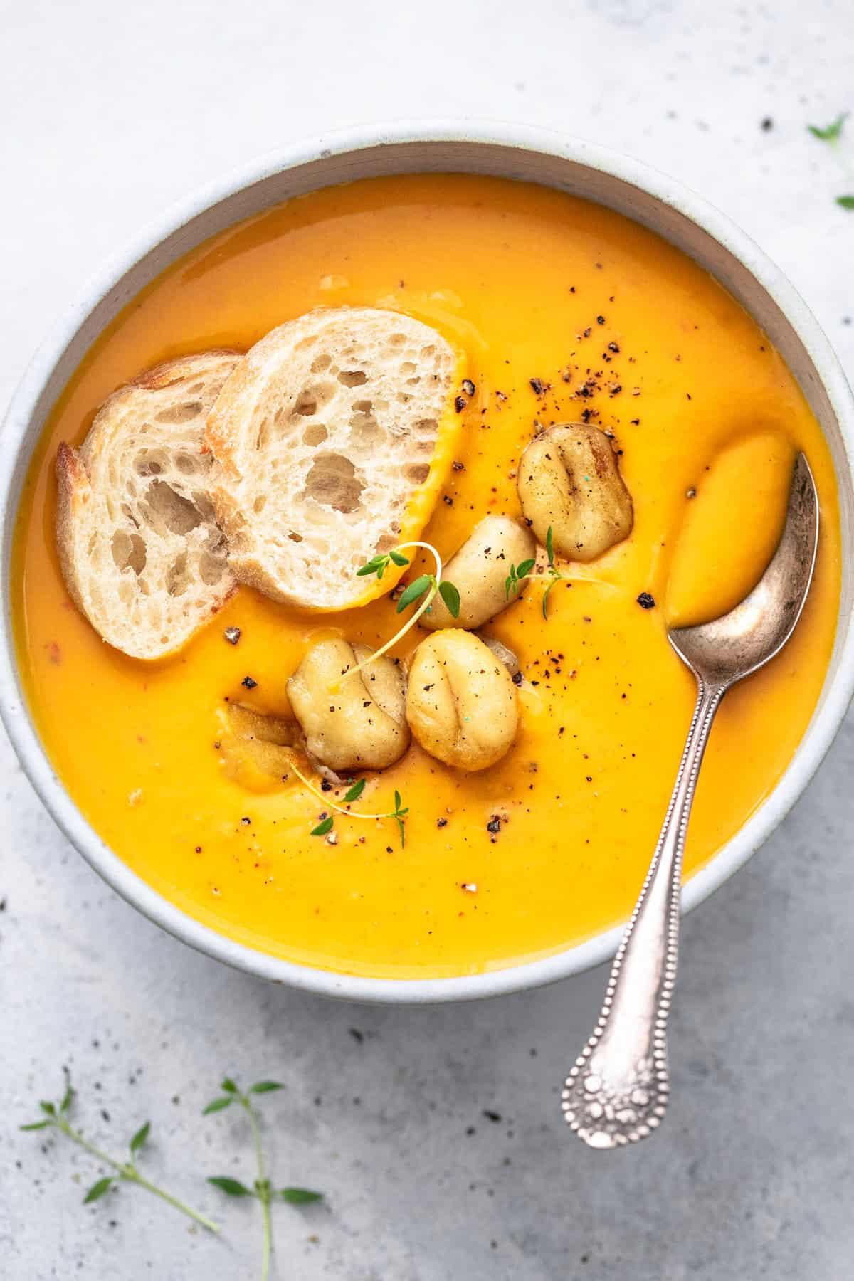 butternut squash soup in bowl with spoon, gnocchi, and croutons