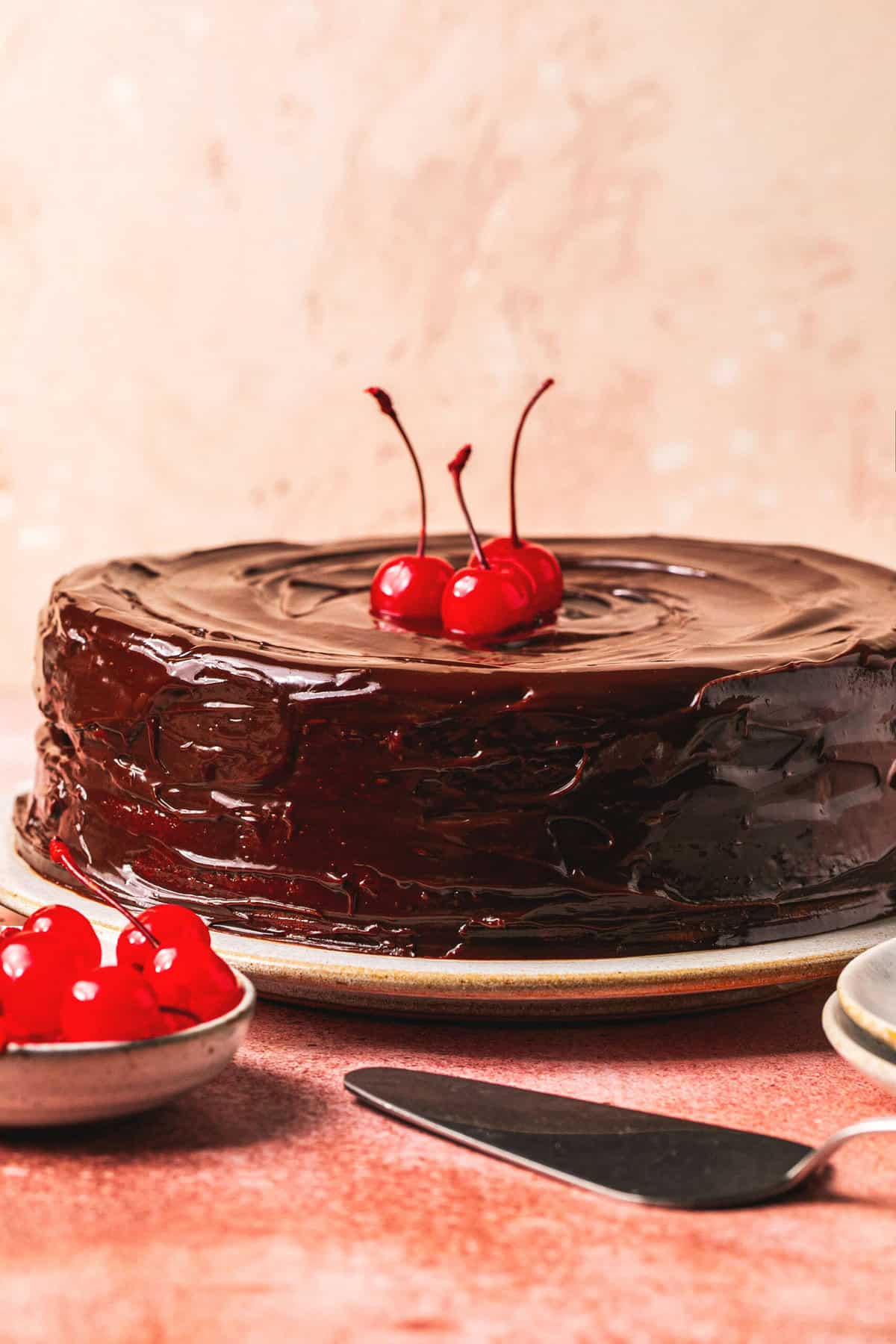 chocolate frosted cake on plate with cherries