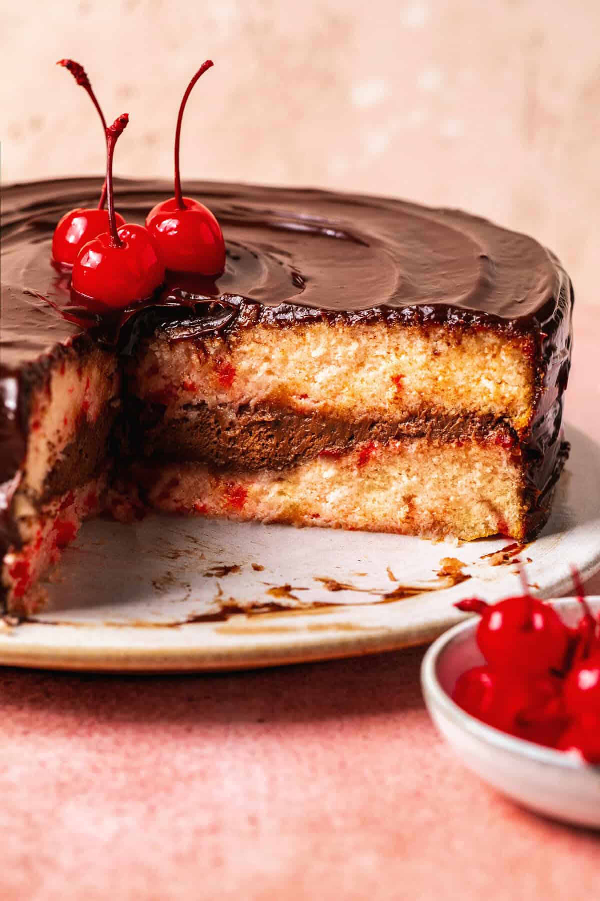 cut layer cake with chocolate frosting and cherries on top