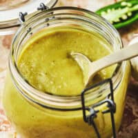 spoon dipping into green enchilada sauce in jar