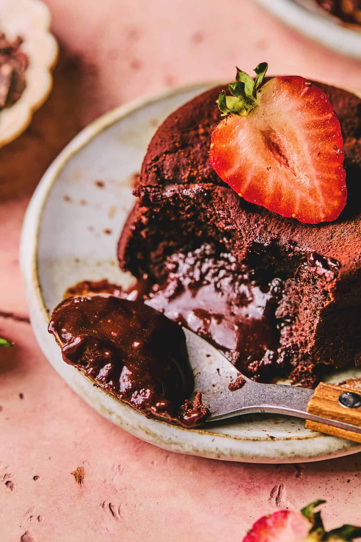 spoon digging into lava cake with strawberry slice