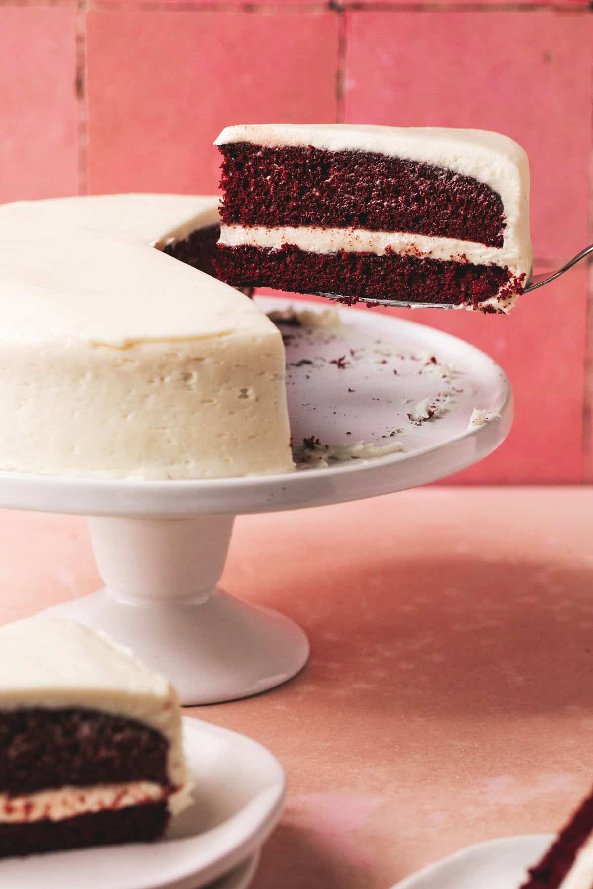 sliced red velvet cake being lifted from cake stand